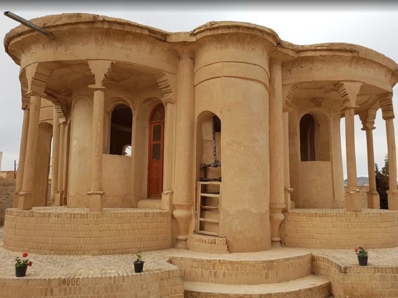 A traditional Abadeh Persian rug featuring a geometric hexagonal medallion on a crimson field